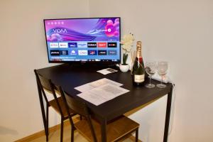 un monitor de ordenador sentado en un escritorio negro con copas de vino en Apartments zum Bühlhof (Julie) en Zúrich