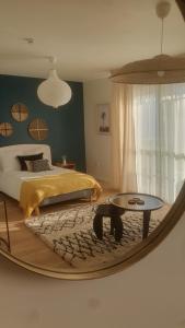 einen Spiegel in einem Schlafzimmer mit einem Bett und einem Tisch in der Unterkunft CAZAM VERNON-GIVERNY in Vernon