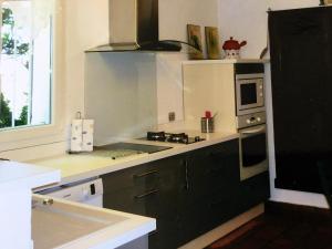 uma cozinha com armários pretos e um balcão branco em Villa de 3 chambres avec piscine privee jardin clos et wifi a Althen des Paluds em Althen-des-Paluds