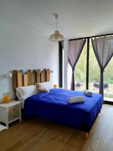 a bedroom with a bed with blue sheets and a large window at Mitjana's House in Cala Galdana