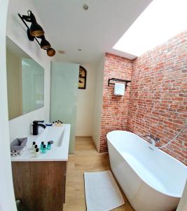 uma casa de banho com uma banheira branca e uma parede de tijolos em Mitjana's House em Cala Galdana