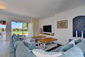 een woonkamer met een blauwe bank en een tv bij Luxuosa Villa Miramar Carvoeiro in Carvoeiro
