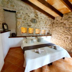 Cette chambre est dotée de 2 lits et d'un mur en pierre. dans l'établissement Agroturismo Son Torrat Apartment Ses Solls, à Petra