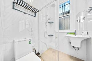 a white bathroom with a shower and a sink at Modern 4B2B house@Glebe in Sydney