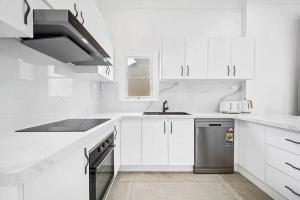 a white kitchen with a sink and a dishwasher at Modern 4B2B house@Glebe in Sydney