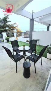 3 chaises et une table sur une terrasse dans l'établissement Sakura Thirty Guest House , Homestay Seri Iskandar, à Seri Iskandar