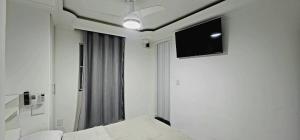 a room with a bed and a flat screen tv at Apart Hotel Farol de Itapuã - Suíte com cozinha completa à 250m da praia e farol de Itapuã in Salvador