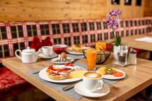 a wooden table topped with plates of food and cups of coffee at Der Rindererhof in Tux