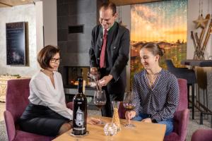 a man and two women sitting around a table with a bottle of wine at Der Rindererhof in Tux
