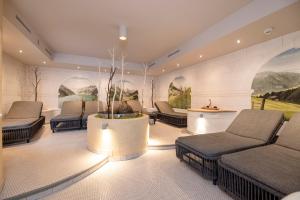 a waiting room with couches and chairs and paintings at Der Rindererhof in Tux