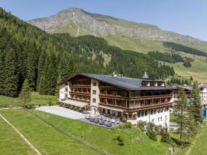 a large building on a hill with mountains in the background at Der Rindererhof in Tux
