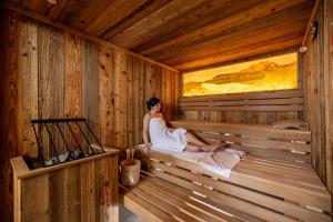 a woman sitting in a wooden sauna at Der Rindererhof in Tux