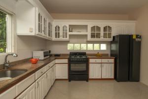 a kitchen with white cabinets and a black refrigerator at Dawn Beach Estate - 3 bedroom Apartment Villa villa in Dawn Beach