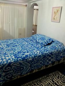 a bedroom with a bed with a blue comforter at Palma del Mar 2 in Puerto Baquerizo Moreno