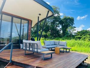 a porch with a couch and tables on a deck at Houttuyn Wellness River Resort in Paramaribo