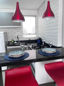 a kitchen with two plates and wine glasses on a counter at “Estúdio 116” - Espaço Gourmet próximo da praia. in Praia Grande