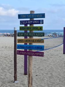 a sign on the beach with many signs on it at “Estúdio 116” - Espaço Gourmet próximo da praia. in Praia Grande