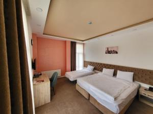 a hotel room with two beds and a desk at Venera Hotel in Baku