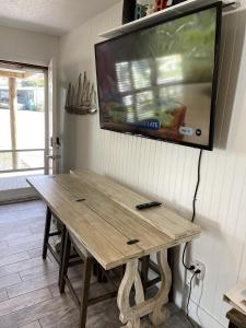 une télévision suspendue sur un mur avec une table en bois dans l'établissement Sunny Delight I, à Cap Carnaveral
