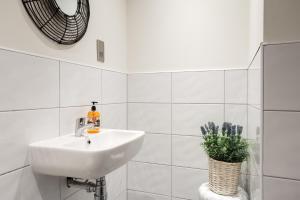 ein weißes Badezimmer mit einem Waschbecken und einem Spiegel in der Unterkunft Modern 2 Bedroom with 75” TV & Free Wi-Fi in Bradford