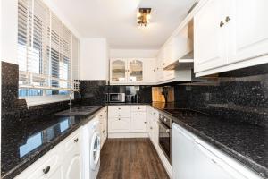 a kitchen with white cabinets and black counter tops at Gorgeous 2BDR Flat in Shoreditch in London