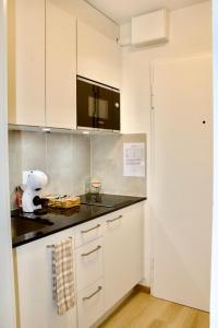 a kitchen with white cabinets and a black counter top at Apartments zum Bühlhof (Alfred) in Zurich