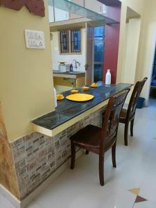 a kitchen with a counter with a table and chairs at Soniya Service Apartment in Tirunelveli