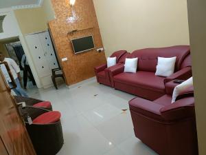 a living room with two red couches and a tv at Soniya Service Apartment in Tirunelveli