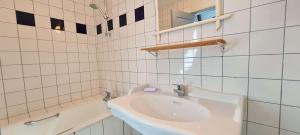 a white sink in a white tiled bathroom at Maison de pays avec étage in La Couarde-sur-Mer