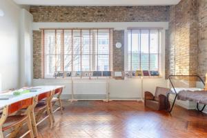 Tastefully Curated Mezzanine Studio Flat Hackney! في لندن: غرفة مع طاولة وكراسي ونوافذ