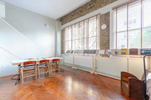 Tastefully Curated Mezzanine Studio Flat Hackney! في لندن: غرفة فارغة فيها طاولات وكراسي ونوافذ