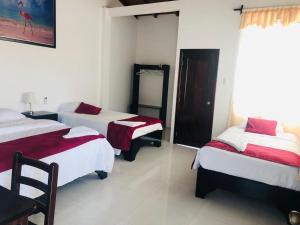 Habitación con 2 camas y sábanas rojas y blancas. en Hostal Las Fragatas, en Puerto Villamil