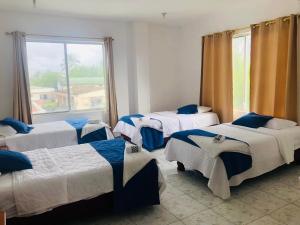a group of four beds in a room with a window at Hostal Las Fragatas in Puerto Villamil