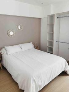 a bedroom with a large white bed and shelves at Rousquille: Patio au RDC d'une maison calme in Port-Vendres