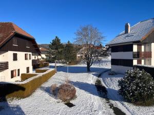 a yard covered in snow next to two buildings at Jour meilleur à Métabief in Métabief