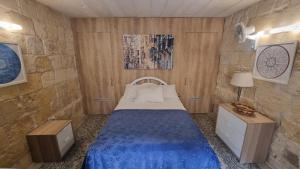 a bedroom with a bed with a blue bedspread at Servants' Quarters Studio Apartment in Valletta