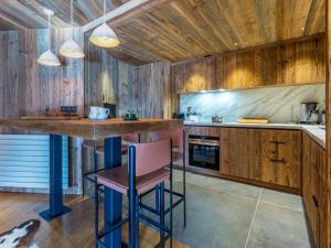a kitchen with wooden walls and a bar with stools at Appartement luxe 4 pièces + studio, terrasse Sud, centre Val-d'Isère, 2023, 8 personnes - FR-1-694-149 in Val dʼIsère