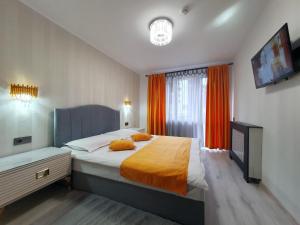 a bedroom with a large bed with orange curtains at Irish House in Sinaia