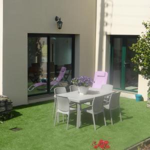 un patio con mesa y sillas sobre hierba en Gite Paradis des Oiseaux du jardin, en Quédillac