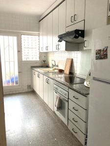 a kitchen with white cabinets and a sink and a refrigerator at Chambre charmante chez habitant in Valencia