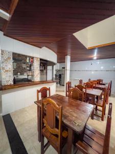 um restaurante com mesas e cadeiras de madeira e uma cozinha em pousada Vitoria em Morro de São Paulo
