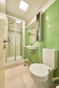 a green tiled bathroom with a toilet and a shower at Inglesinhos Convento 3 - Bright Apartment in Lisbon