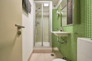 a green tiled bathroom with a shower and a sink at Inglesinhos Convento 3 - Bright Apartment in Lisbon