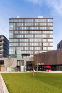 un edificio de cristal alto con un campo de césped delante de él en IntercityHotel Enschede en Enschede