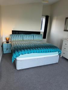 Schlafzimmer mit einem Bett mit blauer Bettwäsche und blauen Kissen in der Unterkunft Doc Fictoria in Caernarfon