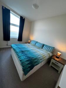 Schlafzimmer mit einem Bett mit blauer Bettwäsche und einem Fenster in der Unterkunft Doc Fictoria in Caernarfon
