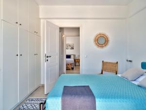 een witte slaapkamer met een blauw bed en een tafel bij Paros Luxury Villa 2mins from the beach in Piso Livadi