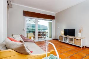 a living room with a couch and a tv at Casa do Mar - Sea view - Wifi - Barbecue in Sesimbra