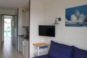 een woonkamer met een bank en een tv aan de muur bij "L'ÉVASION Ô SOLEIL" Appartement 4 personnes, vue dégagée sur le golf, accès parc aquatique gratuit in Talmont