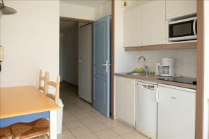 een keuken met witte kasten, een tafel en een magnetron bij "L'ÉVASION Ô SOLEIL" Appartement 4 personnes, vue dégagée sur le golf, accès parc aquatique gratuit in Talmont